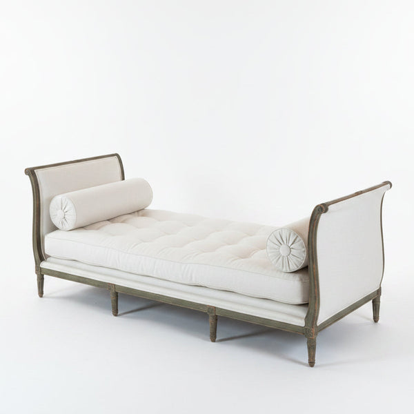 White upholstered daybed with wooden frame on a wooden floor.